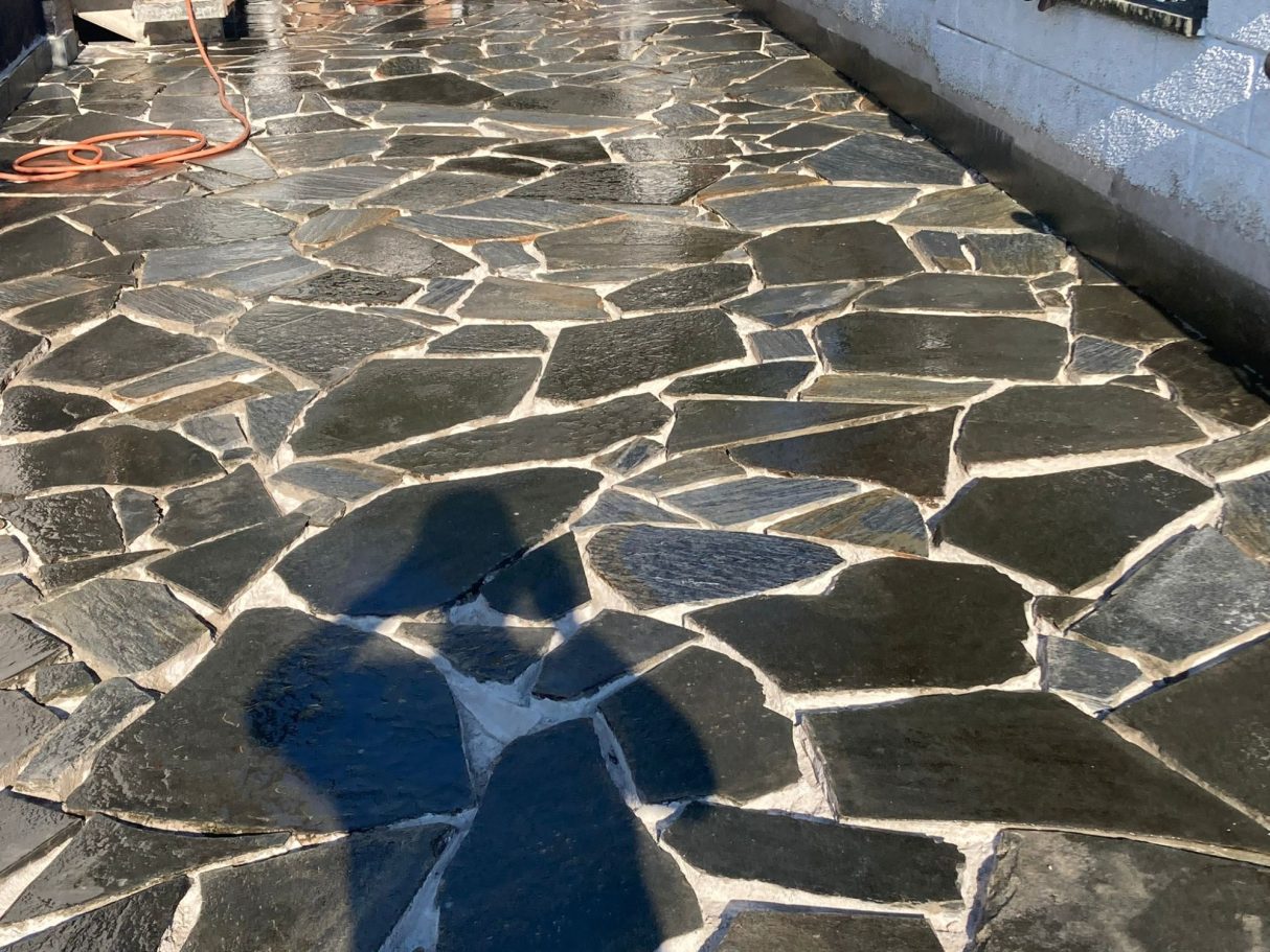 Gepflasterter Weg aus unregelmäßigen Steinen mit reflektierender Oberfläche.